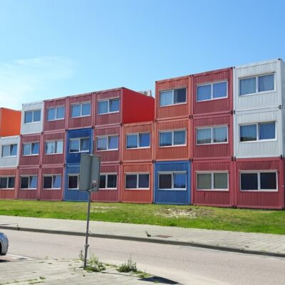 Kolorowe domy stalowe zbudowane z kontenerów mieszkalnych, ustawione w kilku rzędach na przedmieściach.
