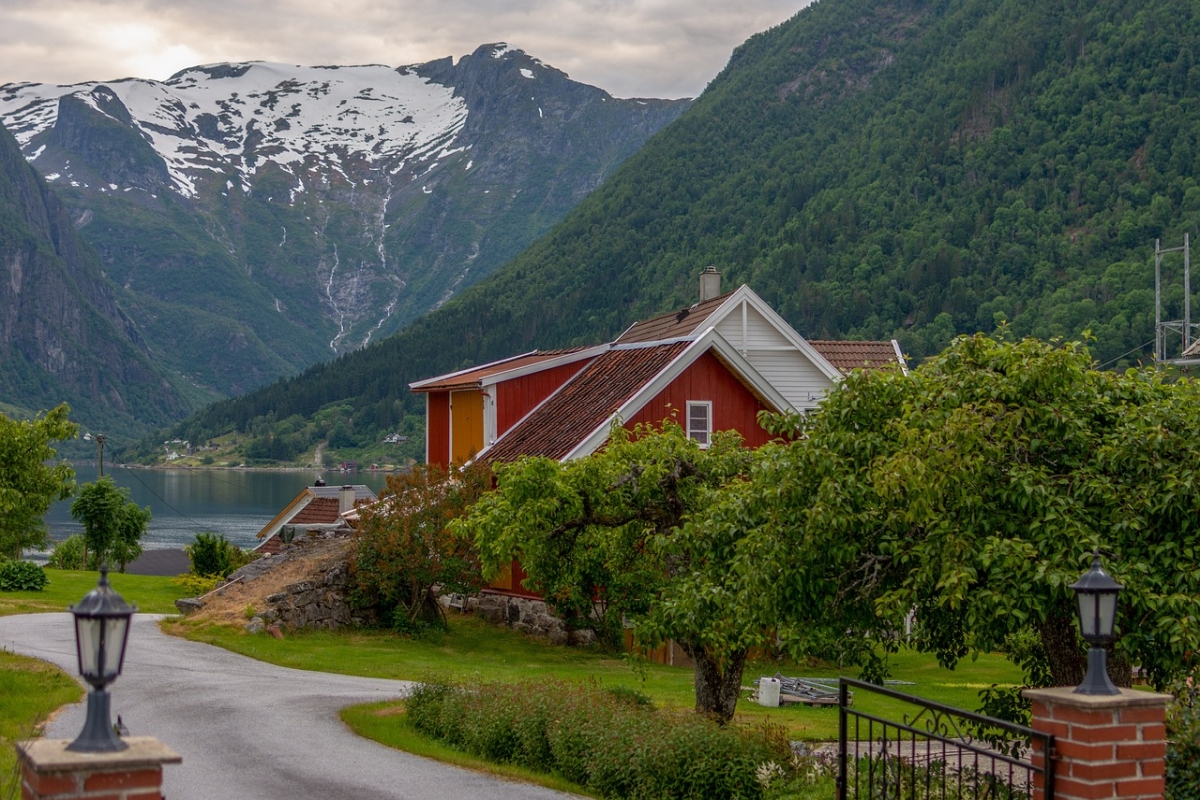 Traditionelle Stahlhäuser in verschiedenen Ausführungen mit roten Ziegeldächern, malerisch gelegen inmitten norwegischer Berge und Grünanlagen in der Nähe des Sees.