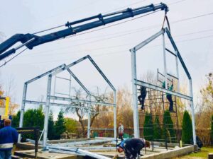Pracownicy montują konstrukcję stalową w trakcie budowy, w tym przypadku dokonano wybór projektu domu stalowego.
