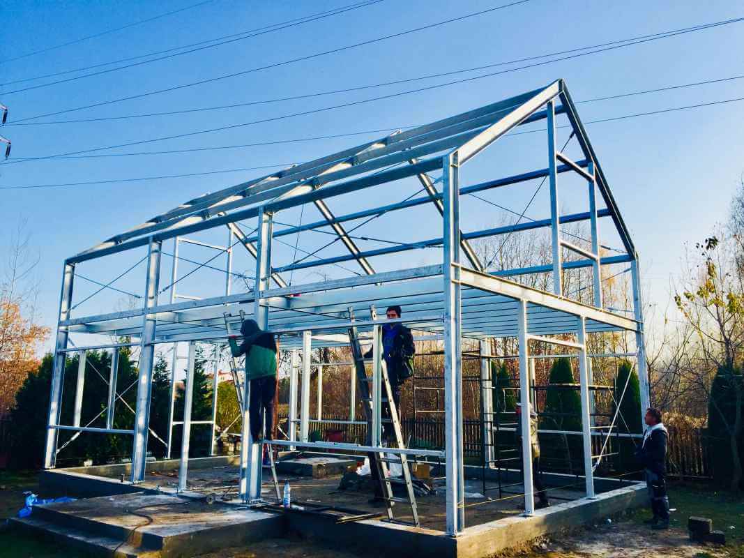 Pracownicy montują konstrukcję z użyciem nowoczesnych technologii w parterowych domach stalowych.