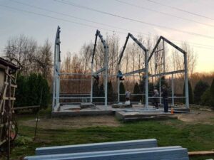 Pracownicy montują stalową konstrukcję, ilustrując wybór firmy budowa hali przemysłowej.