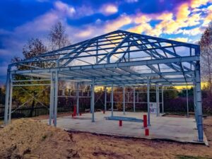 Konstrukcja domu ukazuje proces budowy domu stalowego na tle kolorowego nieba.