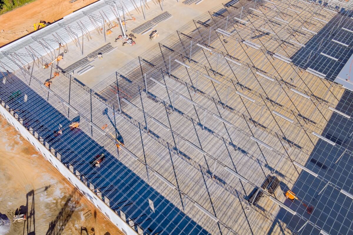 Na zdjęciu widać plac budowy, gdzie trwa budowa stalowej hali, co podkreśla istotny wybór firmy budowa hali stalowej.