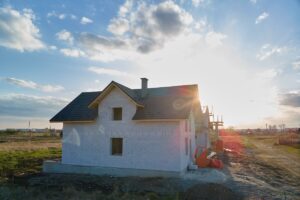 Na zdjęciu widać nowy budynek na tle zachodzącego słońca, a w okolicy znajdują się tradycyjne domy stalowe.