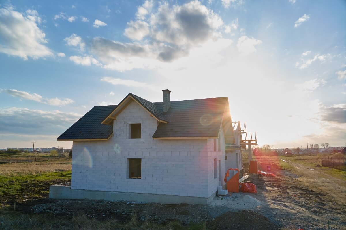 Na zdjęciu widać nowy budynek na tle zachodzącego słońca, a w okolicy znajdują się tradycyjne domy stalowe.