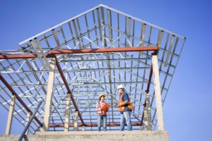 Robotnicy omawiają postępy na placu budowy, gdzie czas budowy domów stalowych jest kluczowy.