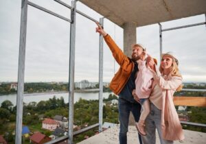 Rodzina ogląda plac budowy, zastanawiając się nad kosztami budowy domu stalowego.