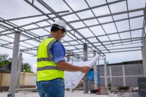 Ein Ingenieur prüft die Baupläne während der Bauphase einer Stahlhalle.